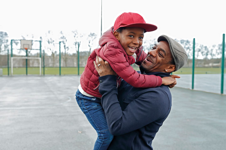 Smiling man holding up happy child