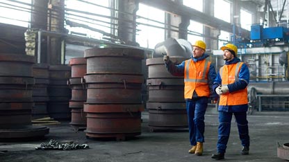 Deux hommes en gilets de sécurité se promenant à travers une usine.
