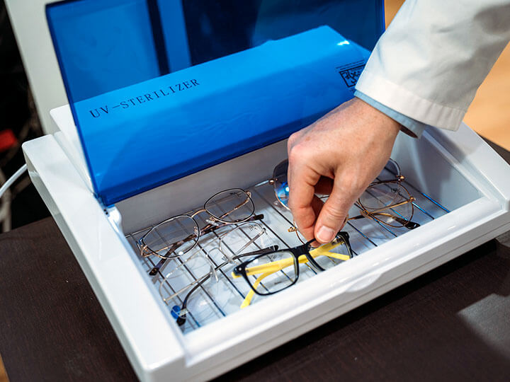 optometrist disinfecting several pairs of eyeglasses in UV germicidal sterilizer