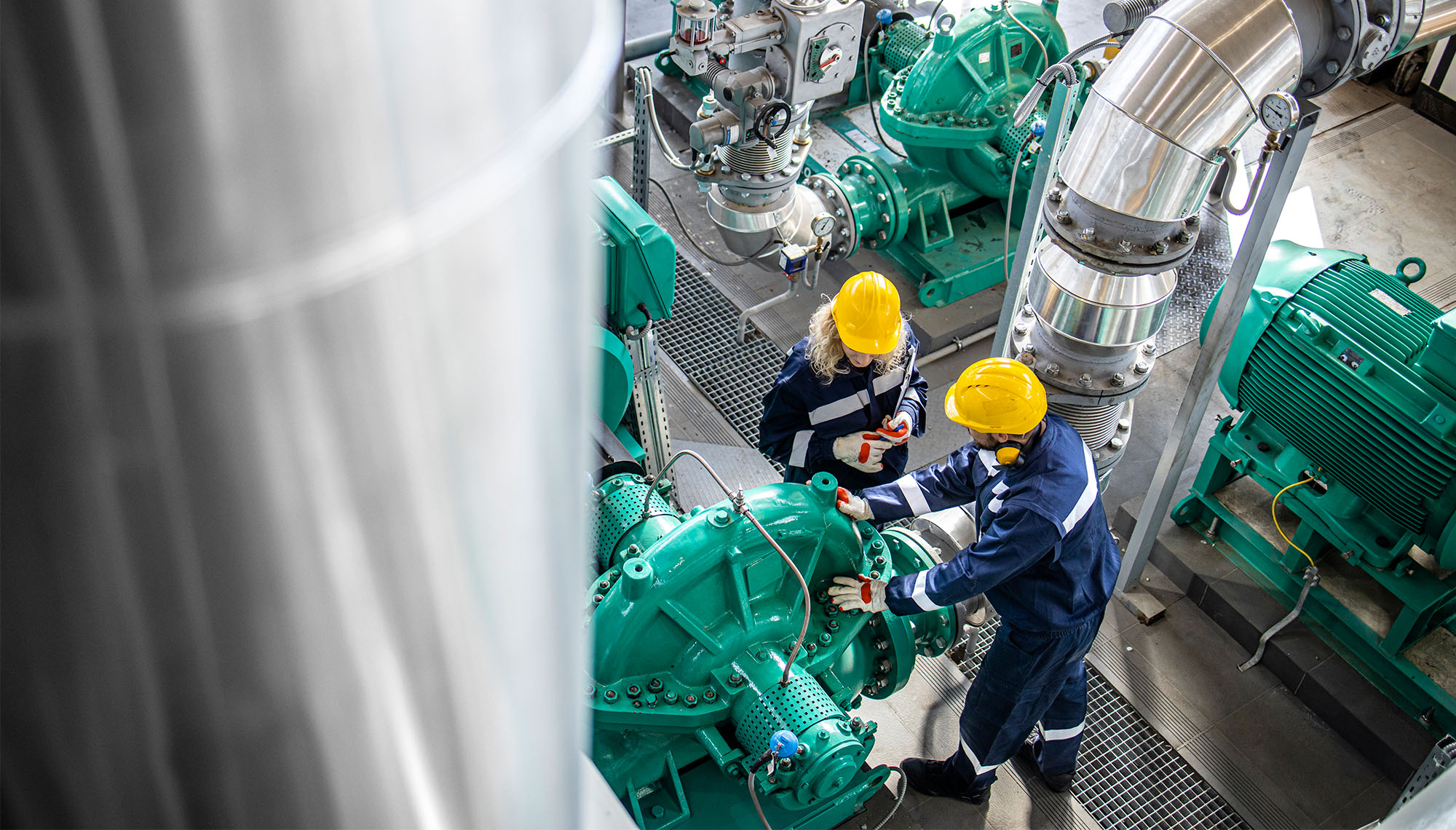 Gas and oil industrial workers working together and checking pipeline and engine pumps in factory.